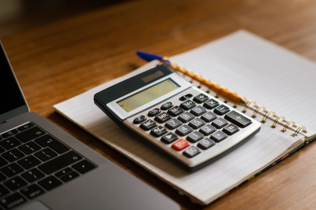 Ordinateur portable, calculatrice et documents de gestion sur un bureau