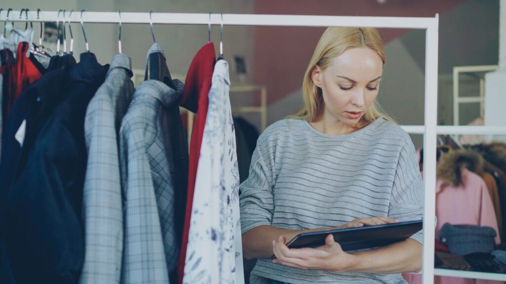 Employée vérifiant le stock sur une tablette dans un magasin de vêtements